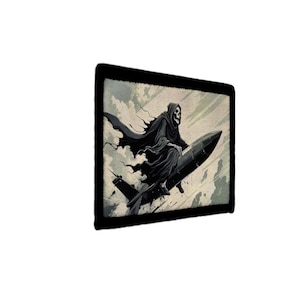 May include: A rectangular wall art print featuring a hooded skeleton figure in a black robe riding a dark grey missile through a cloudy sky. The artwork is framed with a thick black border and displays a muted colour palette of greys and whites.