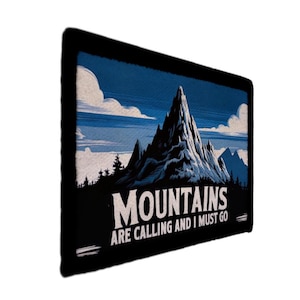 Könnte beinhalten: Rechteckiges Wandbild mit einer Bergillustration. Das Bild zeigt einen blauen Himmel mit weißen Wolken, einen schwarzen Rahmen und den Text "MOUNTAINS ARE CALLING AND I MUST GO" in Weiß.