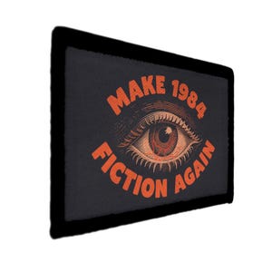 May include: Black rectangular patch with a black border. The patch features an orange eye illustration with the text "MAKE 1984 FICTION AGAIN" in orange, vintage-style lettering.