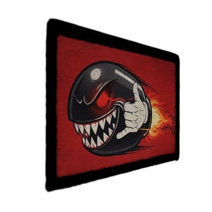 May include: A rectangular patch featuring a cartoon bullet with a menacing expression. The black bullet has sharp white teeth, red eyes, and a white hand giving a thumbs-up. Flames trail behind it against a red background.