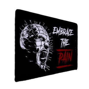 May include: Black rectangular graphic with a white and grey illustration of a face with pins and an open mouth. The text "EMBRACE THE PAIN" is in white and red.