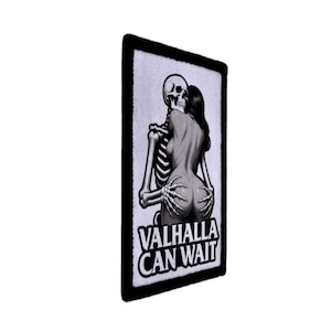 May include: A black and white patch featuring a skeleton embracing a woman. The woman is facing away, and the skeleton's hands are on her buttocks. The text "VALHALLA CAN WAIT" is at the bottom of the patch.