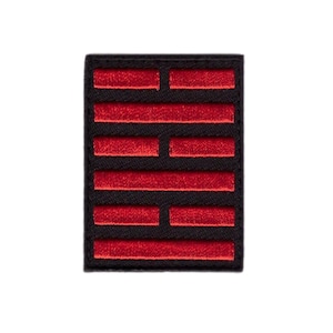 May include: A black rectangular patch featuring a red embroidered design. The design comprises several horizontal red bars of different lengths, arranged symmetrically. The patch has a black border and is set against a white background.