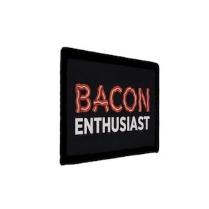 Könnte beinhalten: Ein schwarzer rechteckiger Aufnäher mit den Worten "BACON ENTHUSIAST" in Weiß und Rot. Das Wort "BACON" ist so gestaltet, dass es wie Speckstreifen aussieht. Der Aufnäher hat einen schwarzen Rand.