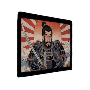 May include: A rectangular print featuring a stern-faced samurai in traditional armor, holding a katana. The background includes a rising sun design with red and white stripes, and a mountain range. The artwork has a vintage, illustrative style.