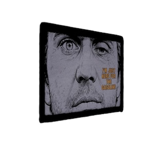 May include: A rectangular wall art piece featuring a black and white sketch of a person's face with intense eyes. The text "I'M JUST HERE FOR THE GASOLINE" is printed in orange capital letters on the right side of the image within a black frame.
