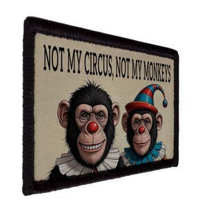 Op de afbeelding: Rechthoekige patch met de tekst "NOT MY CIRCUS, NOT MY MONKEYS". De patch toont twee cartoonapen met rode neuzen en witte ruches kragen. Eén aap draagt een clownshoed.