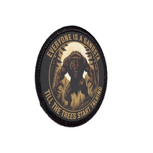 Könnte beinhalten: Ein runder, schwarzer Aufnäher mit dem Text "EVERYONE IS A GANGSTA TILL THE TREES START TALKING". Der Aufnäher zeigt einen braunen Werwolf in einer Waldszene mit roten Augen.