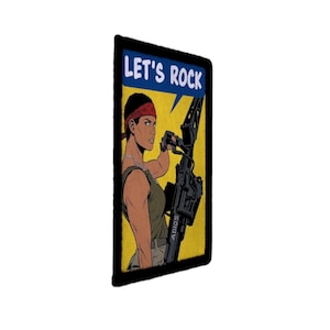 May include: A rectangular patch with a pop art style illustration. The image features a woman with a red headband holding a large weapon. The text "LET'S ROCK" is in a blue banner at the top. The background is yellow.