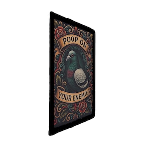 May include: A rectangular art print featuring a pigeon illustration with the text "POOP ON YOUR ENEMIES." The artwork has a black border and is surrounded by ornate floral and scroll designs in red, gold, and green.