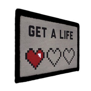 May include: A rectangular, pixelated design with the words "GET A LIFE" in gray block letters. Below the text are three pixelated hearts, one red and two outlined in black. The design has a black border and is set against a light gray background.