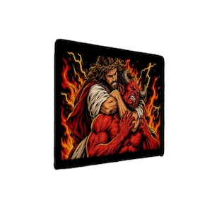 May include: A rectangular wall art print featuring a graphic illustration of a figure with long brown hair and a crown of thorns grappling with a red horned demon. The scene is set against a backdrop of bright orange and yellow flames and lightning.
