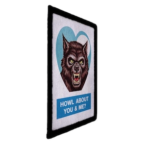May include: A rectangular patch with a black border features a snarling werewolf inside a light blue heart. Below the heart is a blue rectangle with the text "HOWL ABOUT YOU & ME?"