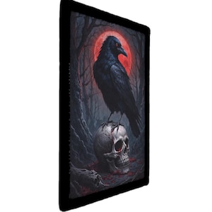 以下が含まれることがあります： 額装されたアートワークは、赤い月と暗い森を背景に、人間の頭蓋骨の上に止まっている黒いカラスを描いています。 このアートワークは、暗い色のパレットを持つゴシック様式をテーマにしています。