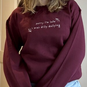 May include: A maroon sweatshirt with white text that reads "sorry i'm late *sparkles* i was dilly dallying *sparkles*"