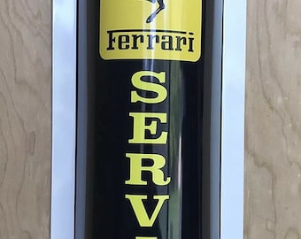 Puede incluir: Un letrero cilíndrico negro y amarillo con el logotipo de Ferrari y la palabra "SERVICE" en letras grandes amarillas.