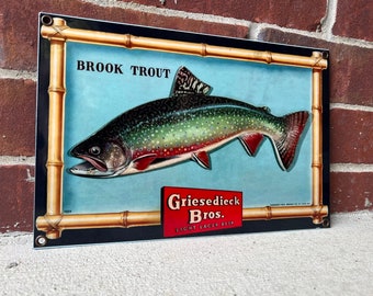 May include: A vintage metal sign featuring a brook trout illustration. The fish is depicted with green, red, and black markings against a light blue background. The sign includes the text "Brook Trout" and "Griesedieck Bros. Light Lager Beer."