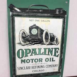 May include: Vintage metal sign advertising Opaline Motor Oil, a product of Sinclair Refining Company in Chicago. The sign features a green background with a black and white illustration of a vintage car and the text "Net One Gallon".