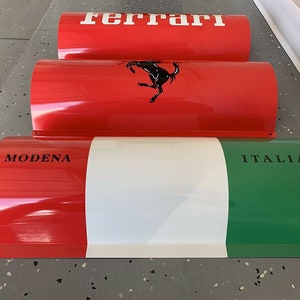 May include: Three red, white, and green cylindrical metal signs with the words "Ferrari", "Modena", and "Italia" printed on them.