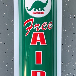 Puede incluir: Un letrero vintage verde y blanco de gasolina Sinclair Dino con el texto "Free Air" en letras rojas.