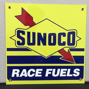 May include: A yellow square sign with a red and blue arrow pointing down. The sign says "SUNOCO RACE FUELS" in white letters.