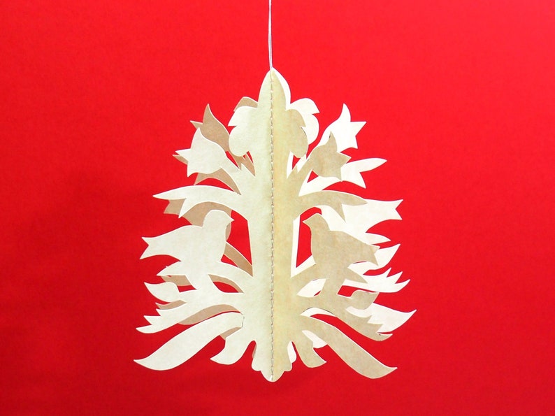 Pode incluir: Um recorte de papel branco de uma &aacute;rvore com p&aacute;ssaros e flores penduradas em uma corda contra um fundo vermelho.