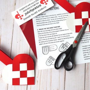 May include: A craft kit for making four Danish heart baskets, called "Julehjerter". The kit includes instructions, red and white paper strips, and a template for cutting out the heart shapes. The instructions show how to weave the strips together to create the baskets.