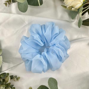 May include: A light blue, fluffy hair scrunchie made of fabric.