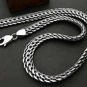 Może przedstawiać: Srebrny naszyjnik z łańcuszkiem z zapięciem na pudełko. Łańcuszek wykonany jest w splocie.