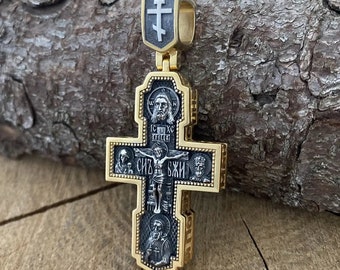 May include: A gold and silver cross pendant with intricate details and religious imagery. The cross features a depiction of Jesus Christ on the front, surrounded by other religious figures.