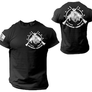 May include: Black t-shirt with a white graphic of crossed rifles and an American flag with the text "One Nation - Under God".