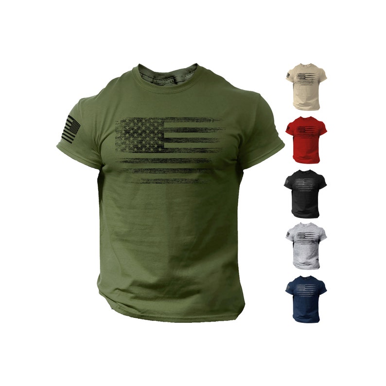 Puede incluir: Una camiseta verde con un gr&aacute;fico de bandera estadounidense en blanco y negro desgastado. La camiseta se muestra en varios colores, incluyendo beige, rojo, negro, gris y azul marino.