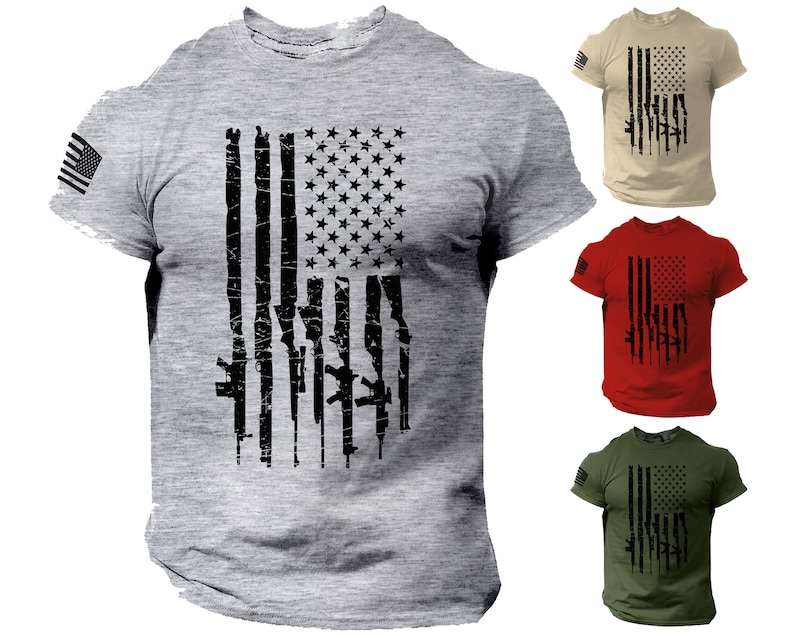 May include: A grey t-shirt with a distressed American flag design featuring a silhouette of guns. The flag is black and the guns are white. The shirt is available in other colors, including tan, red, and green.