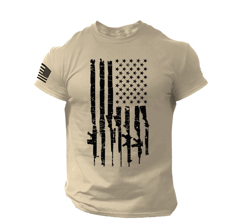 May include: A tan t-shirt with a black and white American flag design. The flag is made up of guns instead of stripes.