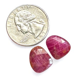 Puede incluir: Dos piedras preciosas de rubí facetadas, cada una del tamaño de una moneda de 25 centavos de dólar estadounidense.