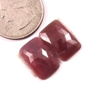 May include: Two pink faceted rectangular gemstones, each about the size of a UK 20 pence coin.