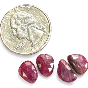 May include: Four faceted ruby gemstones, each approximately the size of a UK 20 pence coin, with a pink-red hue.