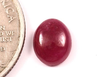May include: A deep red oval cabochon gemstone, approximately the size of a US quarter.