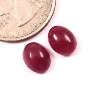 Könnte beinhalten: Zwei ovale, tiefrote Edelsteine, jeder etwa so groß wie eine US-amerikanische 25-Cent-Münze.