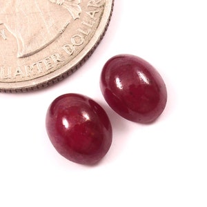 Peut inclure: Deux pierres précieuses rouges de forme ovale, chacune d'environ la taille d'une pièce de 25 cents américaine.