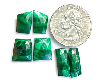 May include: Six green malachite gemstone cabochons in various rectangular and trapezoidal shapes. The stones are faceted and have a green and black marbled pattern. The stones are arranged in a cross shape and are approximately the size of a US quarter.
