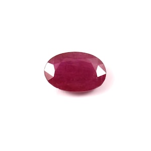 May include: A deep red oval-shaped gemstone with a smooth, polished surface.