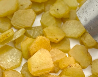 Könnte beinhalten: Nahaufnahme eines Haufens gelber, facettierter Edelsteine. Die Edelsteine sind auf einer weißen Oberfläche verstreut.