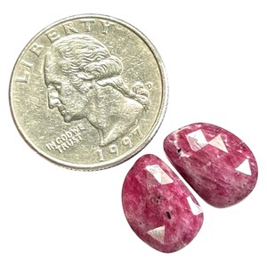 May include: Two pink and white faceted gemstone cabochons. The stones are about the size of a US quarter.