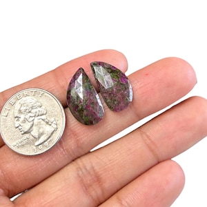 May include: Two teardrop-shaped green and pink gemstones with a faceted finish.