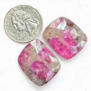 May include: Two pink and white gemstone cabochons with a faceted cut. The stones are approximately the size of a UK 20 pence coin.