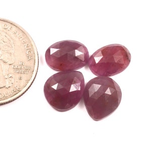 Może przedstawiać: Cztery różowe fasetowane kaboszony z kamieni szlachetnych, każdy w kształcie łzy. Kamienie szlachetne są mniej więcej wielkości amerykańskiej monety 25 centów.