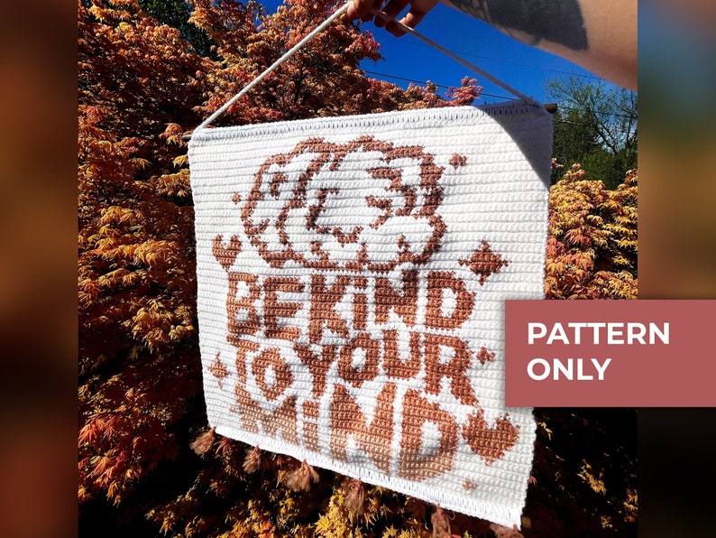 Cute mental health quote design crochet tapestry pattern with the quote "Be Kind To Your Mind" with a brain illustration paired with cute hearts and sparkles.