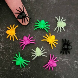 May include: Assortment of colorful plastic spiders, including black, green, yellow, pink, and glow-in-the-dark. These spiders are perfect for Halloween decorations or party favors.