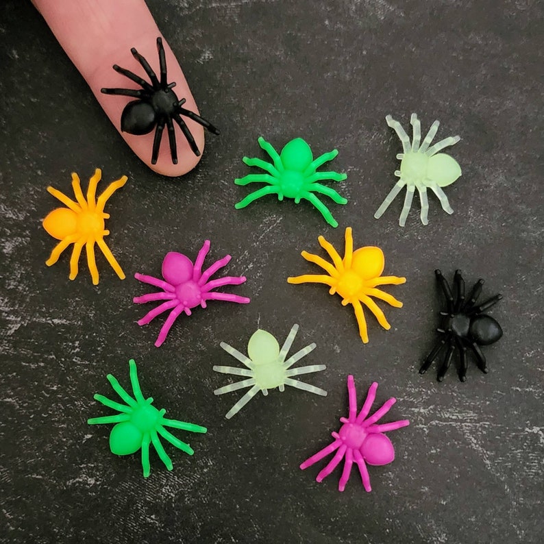 May include: Assortment of colorful plastic spiders, including black, green, yellow, pink, and glow-in-the-dark. These spiders are perfect for Halloween decorations or party favors.
